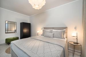 a white bedroom with a large bed and a chandelier at Tina's Tiny Beach House in Slatine