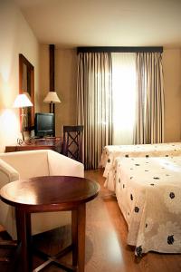 Sala de estar con 2 camas y mesa en Hotel Zerbinetta, en Dílar