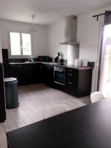 een keuken met zwarte kasten en witte apparaten bij Maison neuve 66 bis in Saint-Martin-la-Rivière