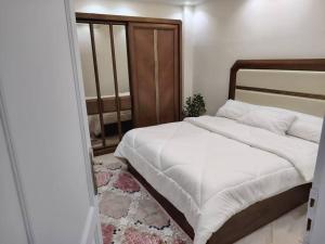 a bedroom with a large bed with white sheets at مدينتي in Kafr Salīm