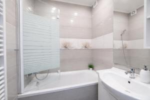 een witte badkamer met een bad en een wastafel bij Comfort 66 Large Family City Home in Miskolc