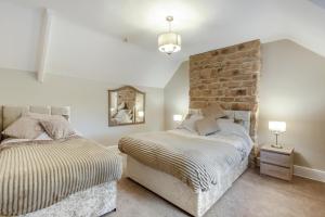 een slaapkamer met twee bedden en een bakstenen muur bij 3 Bed in Mealsgate oc-e33626 in Mealsgate