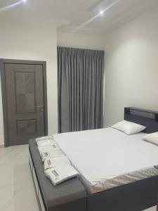 een slaapkamer met een bed met witte lakens en een deur bij Akyamaa's Place Apartments in Accra