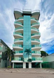 a building with a palm tree in front of it at Hotel Tropical Paracatu Ereli in Paracatu
