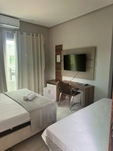 een hotelkamer met twee bedden, een bureau en een televisie bij Serra Village Hotel in Ubajara
