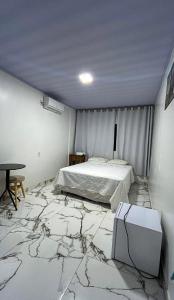 a bedroom with a marble floor with a bed and a table at Hotel WM in Teresina de Goias