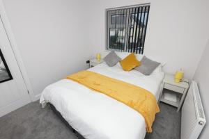 een slaapkamer met een wit bed en een gele deken bij Modern 3 bedroom home refurbished with parking in Wednesbury