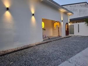ein weißes Haus mit einer Auffahrt davor in der Unterkunft Wanan Cafe & Boutique Hotel in Chon Buri