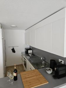 een keuken met witte kasten en een bar met wijnglazen bij Summit View Apartment in Spiez