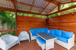 eine Terrasse mit einem blauen Sofa und Stühlen auf einem Holzdeck in der Unterkunft Casa Familia in West Bay