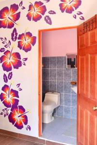 een badkamer met een toilet met bloemen aan de muur bij The Salty Dogs in Playa San Blas