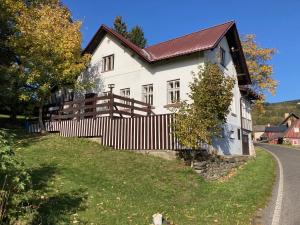 een wit huis met een hek naast een weg bij Chata Hnyk in Zlatá Olešnice