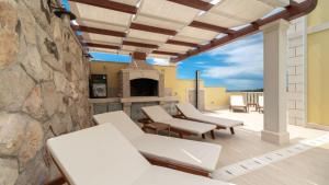 a patio with white chairs and a stone wall at Villa Vanilla by Villas Guide in Smokvica