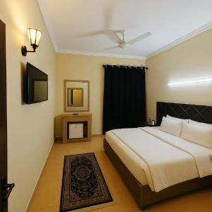 a bedroom with a large bed and a television at Urban Suites in Faisalabad