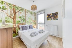 a bedroom with a white bed with towels on it at Cinéhouse, Proche Paris 5 min, 2 chambre in Bobigny