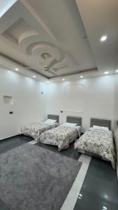 3 posti letto in una stanza con pareti bianche di Mountain Breeze Stay a Sayq