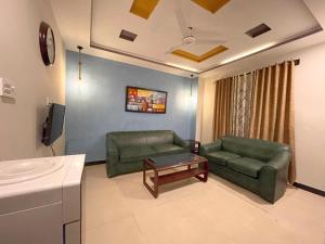 a living room with two green chairs and a couch at OWN IT - 2BHK Brown in Islamabad