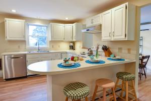 uma cozinha com armários brancos e uma ilha com bancos de bar em Sunroom Mins to Beaches Views of Marsh em Eastham