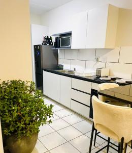 eine Küche mit weißen Schränken und einem Tisch mit einer Topfpflanze in der Unterkunft LSG Delta in Centurion
