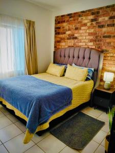 ein Schlafzimmer mit einem großen Bett mit Ziegelwand in der Unterkunft LSG Delta in Centurion