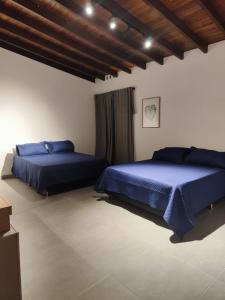 2 letti in una camera da letto con lenzuola blu di Hotel La Casona Estadio a Medellín