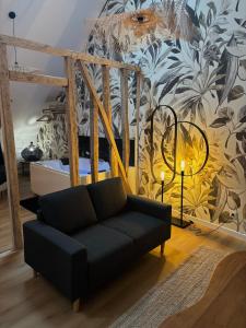 een woonkamer met een zwarte bank en een muurschildering bij Résidence ARTHUS Thamarys in Pierrefonds +12 foto's