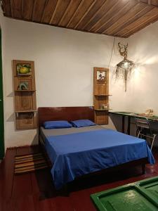 een slaapkamer met een bed met blauwe lakens en een bureau bij Koniminto Hostal in Pijao