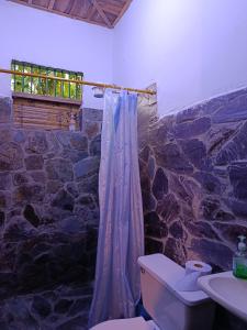 een badkamer met een toilet en een stenen muur bij Koniminto Hostal in Pijao