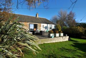 a brick house with a patio in a yard at Mill View Cottage- charming coastal cottage in Saint Monance
