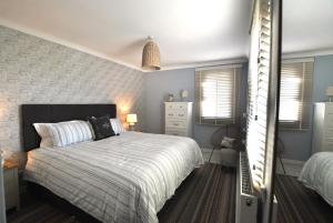 a bedroom with a bed and a dresser and windows at Mill View Cottage- charming coastal cottage in Saint Monance