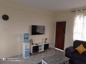 een woonkamer met een bank en een tv aan de muur bij Atlantis City BnB in Nakuru