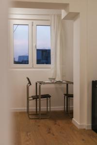 a table and a chair in a room with two windows at Astor Wellness apartman in Belgrade