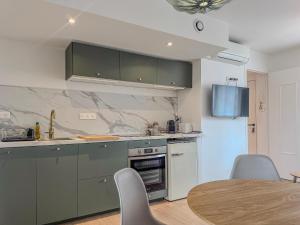 a kitchen with green cabinets and a table with chairs at Liberté Prestige - Tram - Rocade in Fontaine