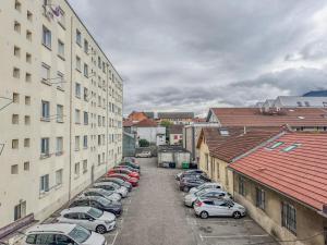 a row of cars parked in a parking lot next to buildings at Liberté Prestige - Tram - Rocade in Fontaine