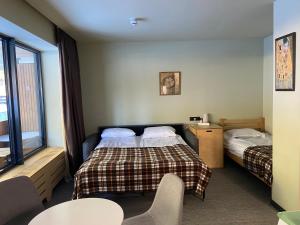 Bakuriani Kohta-Mitarbi Cozy studio B1 110 في باكورياني: غرفة فندق بها سريران وطاولة