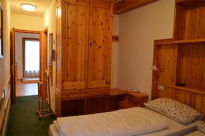 マドンナ・ディ・カンピリオにあるAppartamenti BUCANEVEの木製の壁のベッドルーム1室、ベッド1台が備わります。