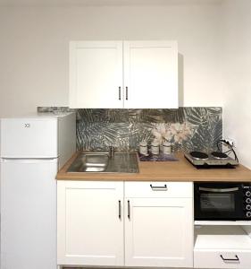 a kitchen with white cabinets and a sink and a refrigerator at Home Sweet Home Forli in Forlì