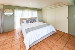 a bedroom with a large bed and a clock on the wall at Hillside Haven in Whanganui +18 photos