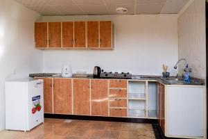 une cuisine avec des armoires en bois et un réfrigérateur blanc dans l'établissement Eco Paradise UAQ Harmony with Nature, à Umm Al Quwain