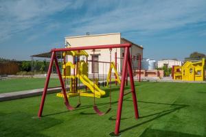 une aire de jeux avec un toboggan jaune sur un terrain vert dans l'établissement Eco Paradise UAQ Harmony with Nature, à Umm Al Quwain