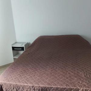 un letto con copriletto viola sopra di Apartamento Beira-mar a Guarapari