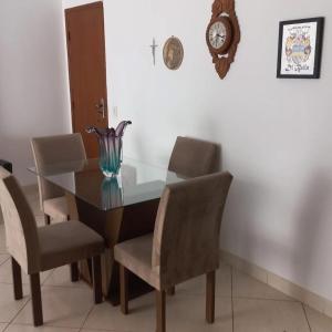 tavolo da pranzo con sedie e orologio sul muro di Apartamento Beira-mar a Guarapari