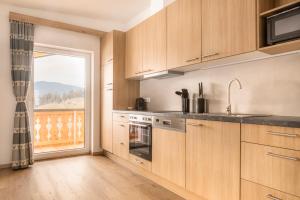 a kitchen with wooden cabinets and a large window at Peterlehen Appartements in Altenmarkt im Pongau +20 photos
