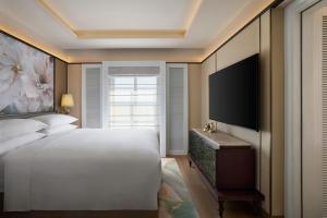 een slaapkamer met een bed en een flatscreen-tv bij Renaissance Goa Hotel in Goa