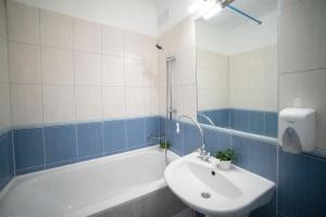 een badkamer met een wit bad, een wastafel en een bad bij Comfort 28 Parkside Comfort in Miskolc