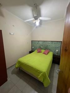 a bedroom with a green bed with a ceiling fan at La casa del varón in Mina Clavero
