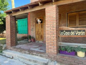 a brick building with a door and a sign on it at La casa del varón in Mina Clavero