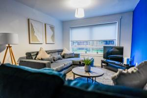 een woonkamer met een bank en een tv bij Sedgebank House in Uphall