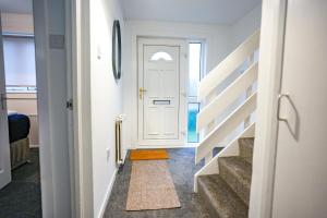 een hal met een witte deur en een trap met een tapijt bij Sedgebank House in Uphall