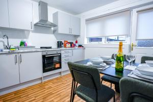 a kitchen with a table and chairs and a kitchen with white cabinets at Sedgebank House in Livingston
